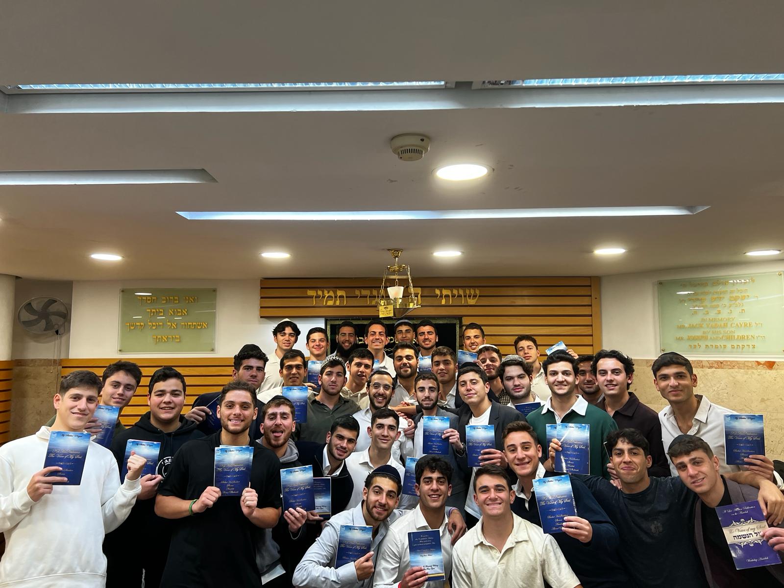 Talmidim holding newly published sefarim together in the Bet Medrash