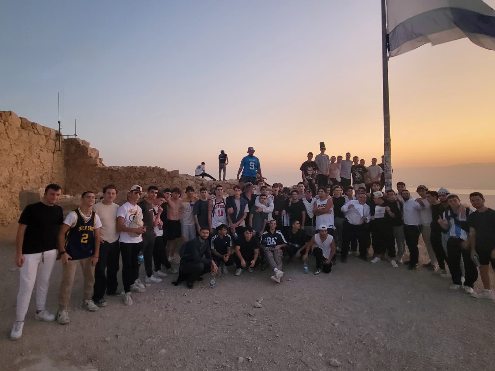 Talmidim of Yeshivat Lev Aharon gathered at sunrise atop Masada beside the Israeli flag