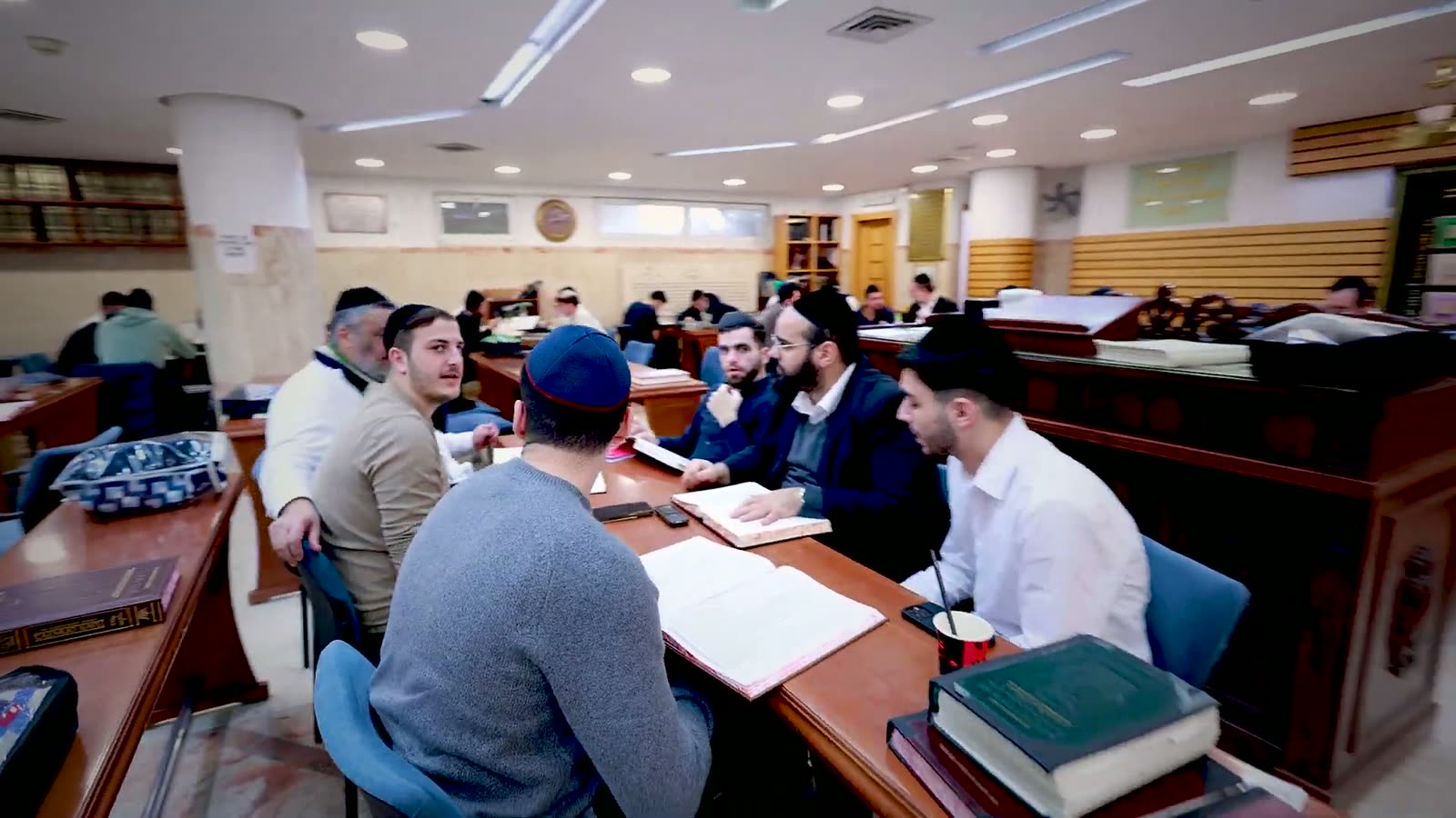 A wide view of the Bet Medrash during seder, tables full of open sefarim