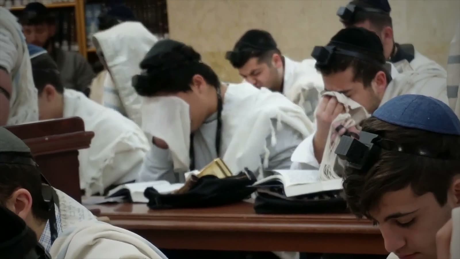 Talmidim in tallitot bent over their sefarim in the Bet Medrash