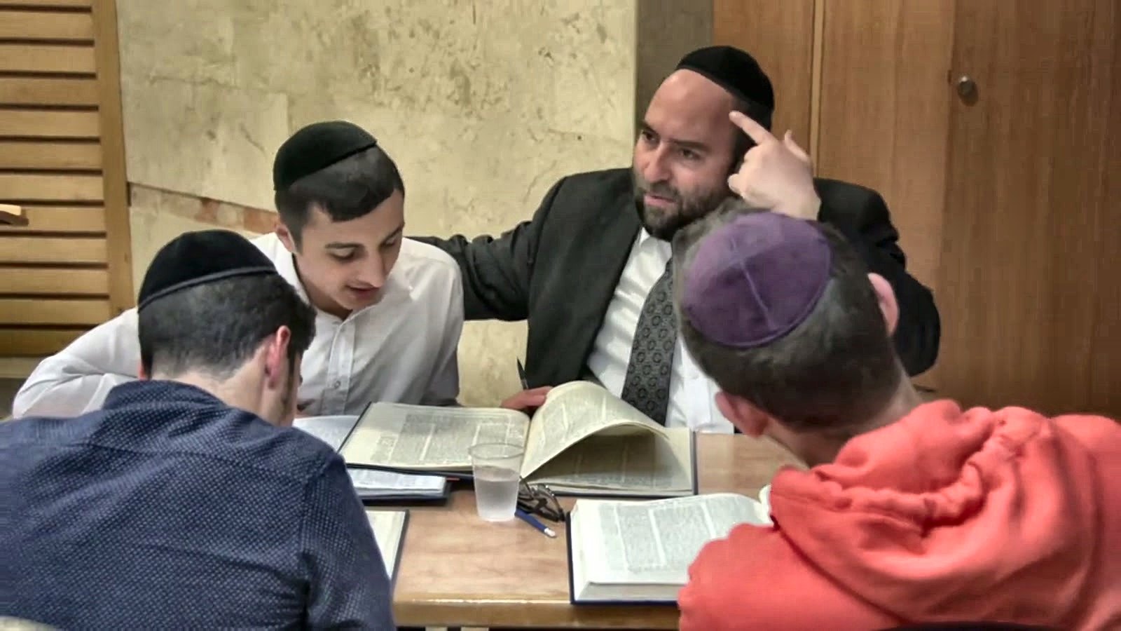 A rebbi learning with boys around a table