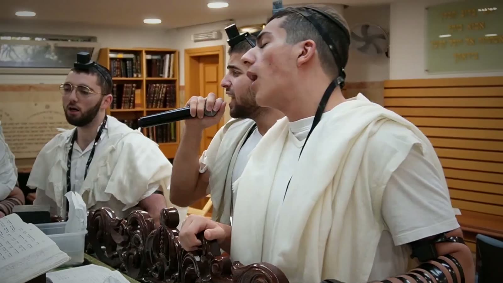 Talmidim in tallitot singing together at the amud
